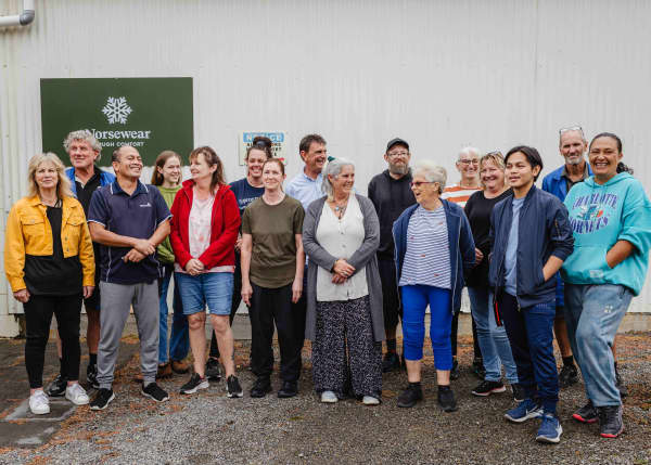 A group of about 16 Norsewear workers stand outside their factory in Norsewood, at the foot of the Ruahine ranges in southern Hawke’s Bay.