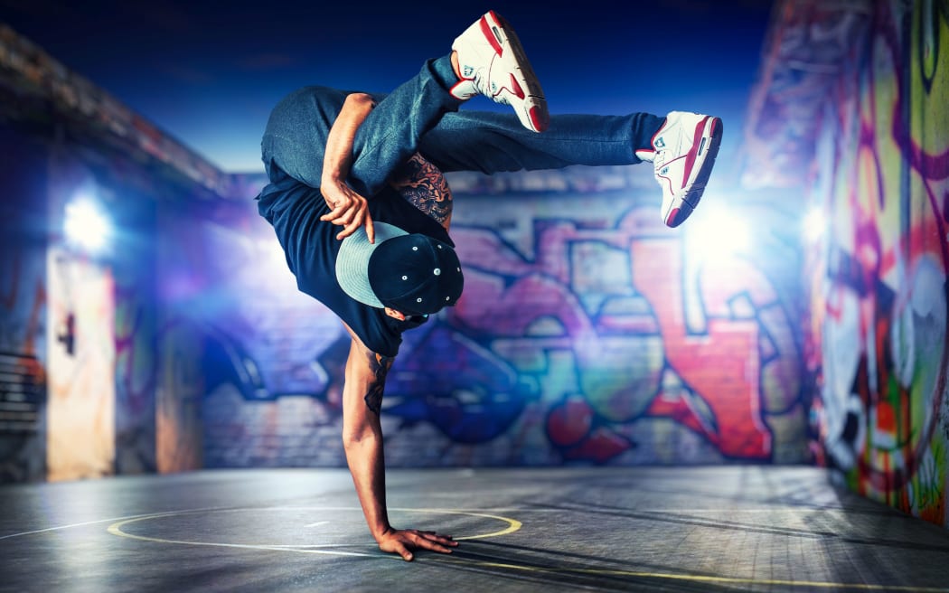 Young man break dancing at night on urban painted walls background