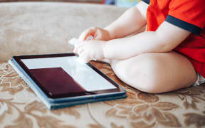 child uses a Tablet PC, hand in focus, without face