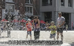 Summer in Wellington, a boy is splashed by the people jumping into the harbour.