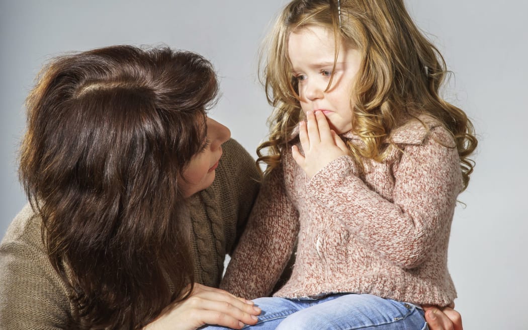 A photo of a mother reassuring her little daughter who is distracted and crying