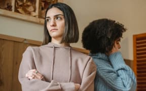 two women facing away from each other and looking unhappy