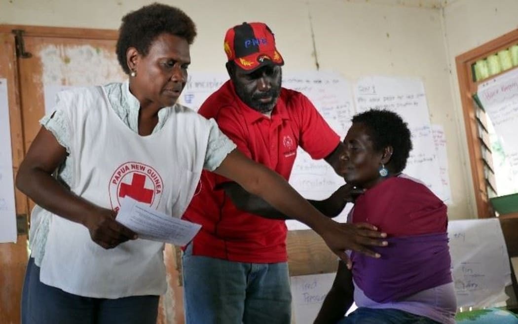 PNG Red Cross Bougainville branch coordinator Aidah Kenneth (left) demonstrates how to stabilize an arm fracture, with the help of first aid trainers Pais Tawoanea (center) and Benedine Siunai (right).