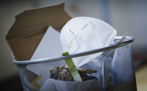 Symbolic photo on the topic ?Äô End of the mask requirement ?Äô. An FFP2 mask is in a garbage can. Berlin, March 10, 2022 (Photo by Thomas Trutschel / Photothek / dpa Picture-Alliance via AFP)