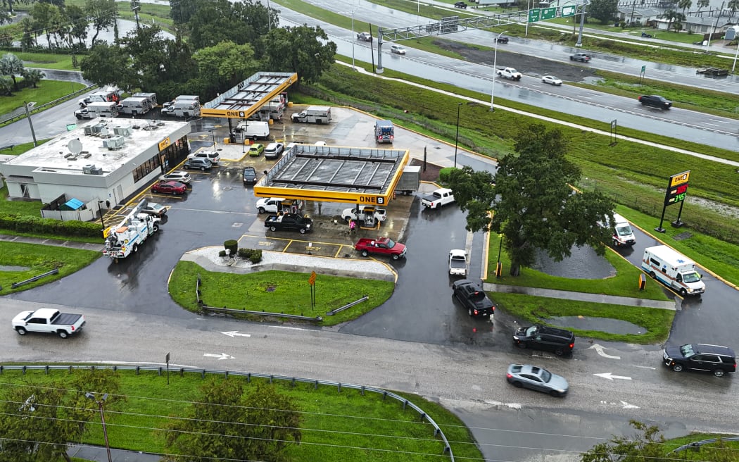 This drone picture shows people lining up in their cars for fuel at a gas station ahead of Hurricane Milton's expected landfall in Bradenton, Florida on October 9, 2024. - Milton regained power on October 8 to become a Category 5 storm with maximum sustained winds of 165 mph (270 kph) as it barrels towards the west-central coast of Florida and is forecast to make landfall late October 9, according to the National Hurricane Center. (Photo by Miguel J. Rodriguez Carrillo / AFP)
