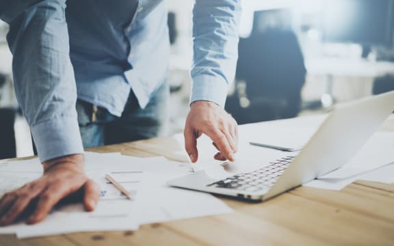 Businessman working in modern cretive studio. Using generic design laptop. Architectural project on table.