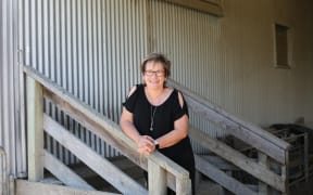 Robyn Dynes leans on railings outside a farm building