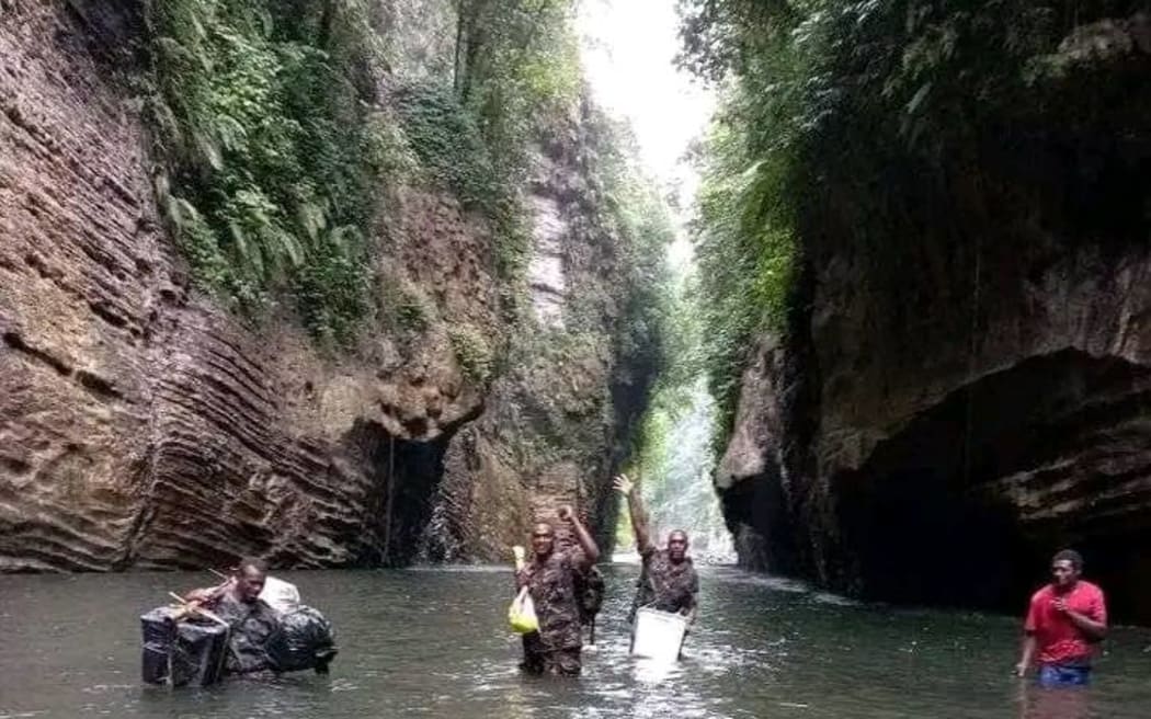 Vanuatu Mobile Force Officers, Private Samuel Bani, Private David Arksai and Corporal David Amos wade through water with ballot boxes.