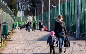 Ukrainian families walk through the Medyka border crossing into Poland after Russia bombarded Ukraine.