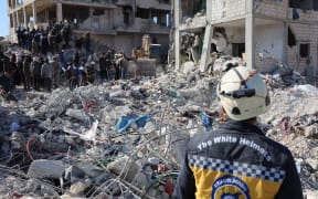 Rescue workers look for survivors amid the rubble of a building in the rebel-held Syrian town of Jindayris on 9 February 2023, three days after a deadly earthquake that hit Turkey and Syria.