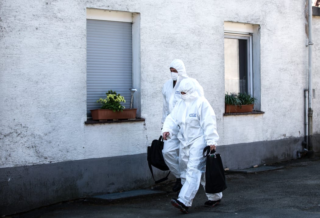 Members of the crime scene unit walking past the house of the accused couple in Hoexter, Germany.