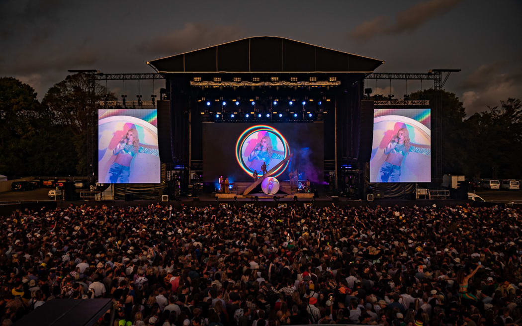 A crowd in front of a large stage watching a musician at night.