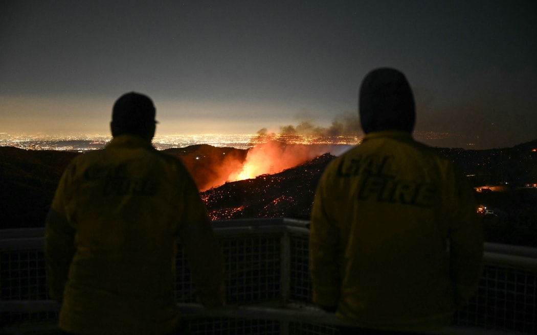 Firefighters monitor as the Palisades fire grows near the Mandeville Canyon neighborhood and Encino, California, on January 11, 2025. The Palisades Fire, the largest of the Los Angeles fires, spread toward previously untouched neighborhoods January 11, forcing new evacuations and dimming hopes that the disaster was coming under control. Across the city, at least 16 people have died as multiple fires have ripped through residential areas since January 7, razing thousands of homes in destruction that US President Joe Biden likened to a "war scene." (Photo by Patrick T. Fallon / AFP)