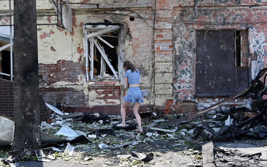 A woman stands among debris next to a recruitment centre building damaged after a drone attack in Kharkiv on 7 July, 2025, amid the Russian invasion of Ukraine.