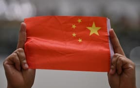 A woman holds up a Chinese flag during a pro-Beijing flash mob at the Pacific Place shopping mall in Hong Kong
