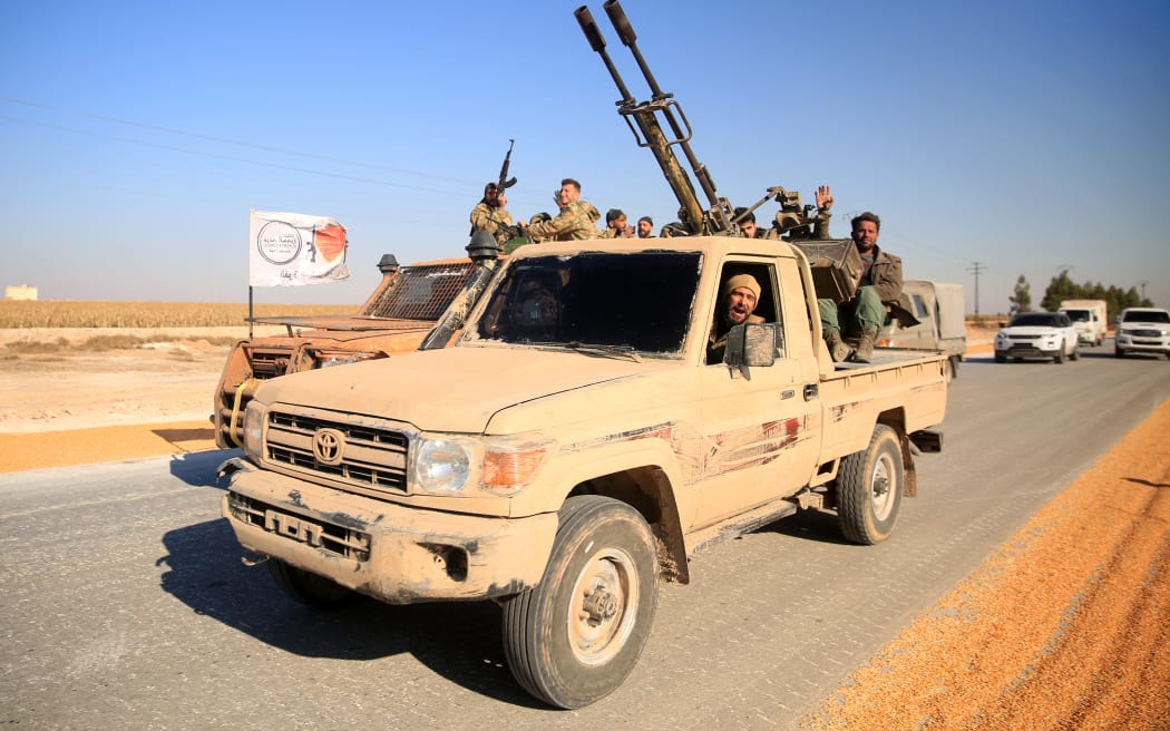 Anti-government fighters ride military vehicles as they drive along a road in the eastern part of Aleppo province on December 1, 2024. - Syria's second-largest city Aleppo has fallen from government control for the first time since the country's conflict began more than a decade ago, a war monitor said on December 1, after a surprise advance by rebels. (Photo by Aref TAMMAWI / AFP)