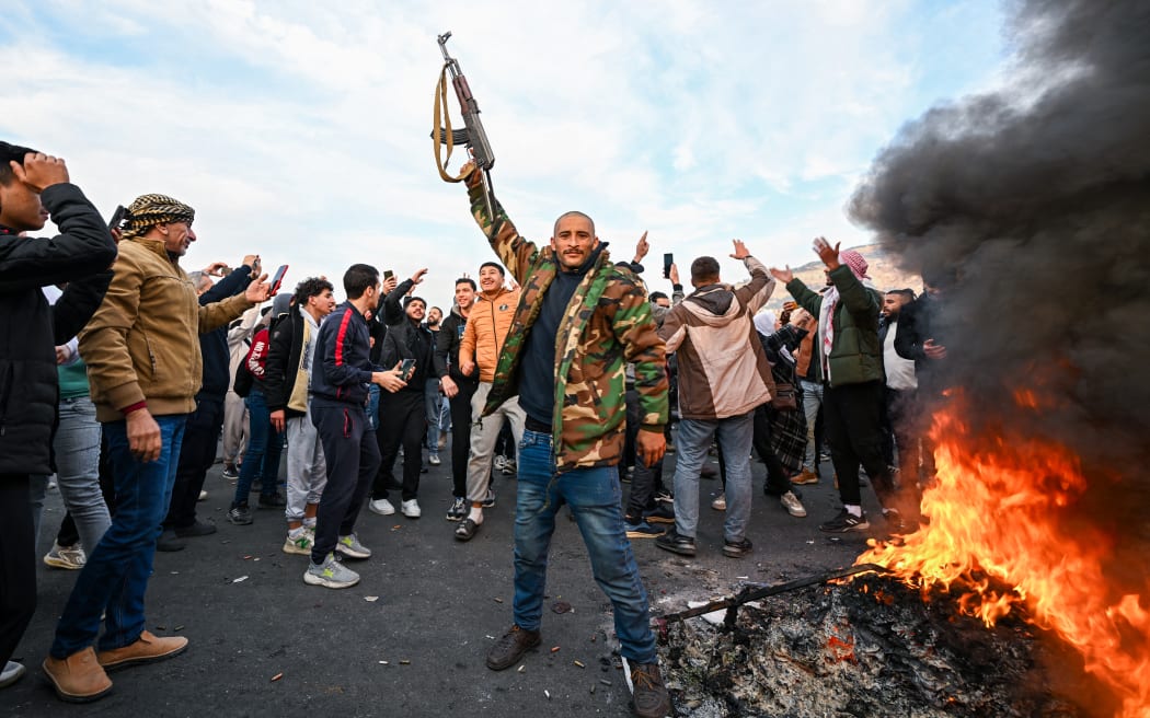 People celebrate at Umayyad Square in Damascus on December 8, 2024. - Islamist-led rebels declared that they have taken Damascus in a lightning offensive on December 8, sending President Bashar al-Assad fleeing and ending five decades of Baath rule in Syria. (Photo by LOUAI BESHARA / AFP)