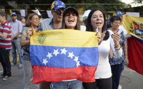Opposition activists celebrate outside polling stations after taking part in an opposition-organized vote to measure public support for Venezuelan President Nicolas Maduro's plan to rewrite the constitution.