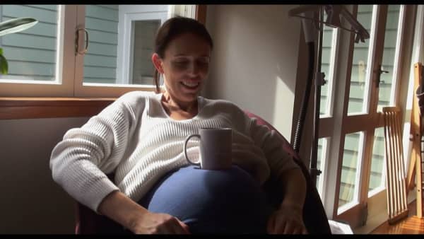 Jacinda Ardern sitting with a mug on her belly, in a clip from a documentary - Prime Minister - about her tenure.
