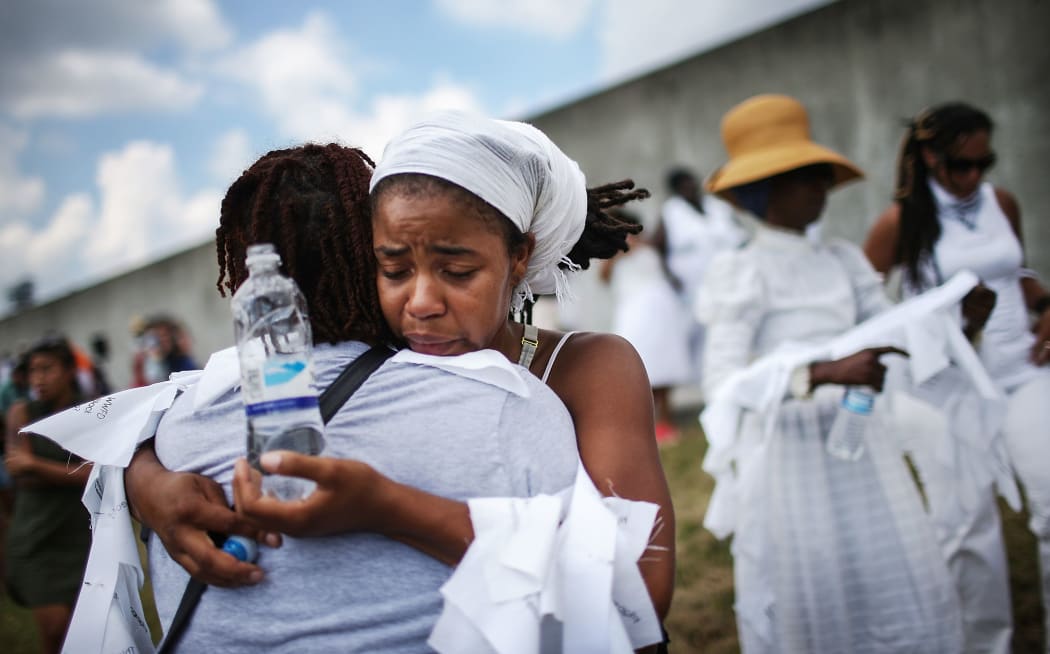 Savannah Shange hugs a woman in front of the repaired levee wall in the Lower Ninth Ward