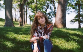 Young woman sitting on grass in a grove of trees