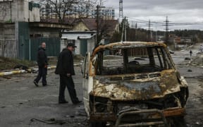 People walk through a street strewn with several dead bodies in Bucha, northwest of Kyiv.