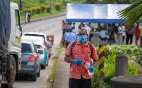 Person walks along the road as security officers check cars in Suva, Fiji on 26 April, 2021.