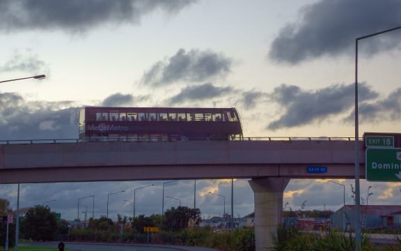 Double decker bus goes on a flyover against a back lit sky in Auckland New Zealand.