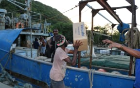Vanuatu disaster officers and the crew of the ship One People form a chain gang to load supplies for evacuees on Ambae.