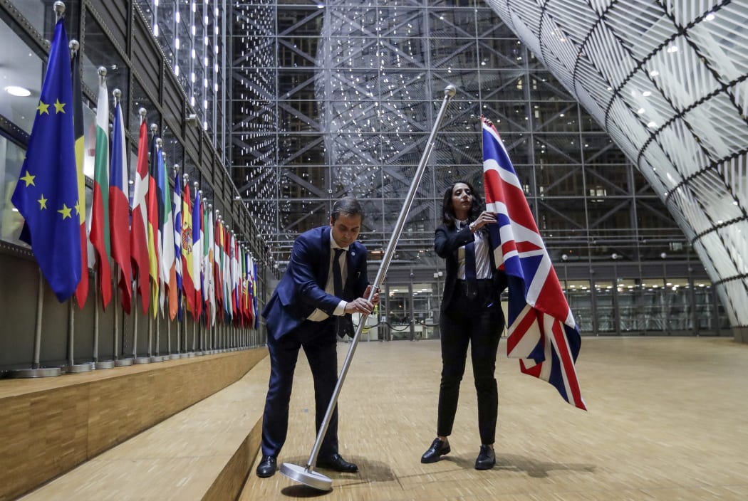 EU Council staff members remove the United Kingdom's flag from the European Council building in Brussels.