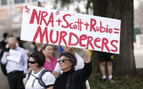 An activist holds up a placard during a rally at the Florida State Capitol building to address gun control on February 21, 2018 in Tallahassee, Florida.