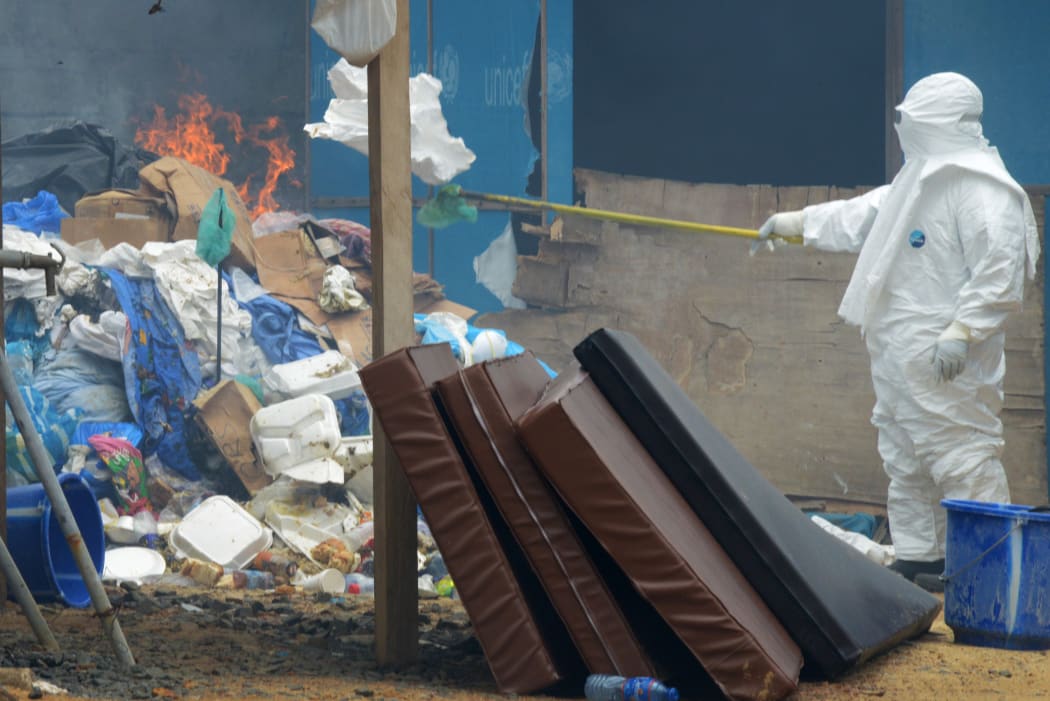 A healthcare worker burns infected items at a hospital in Monrovia, Liberia.
