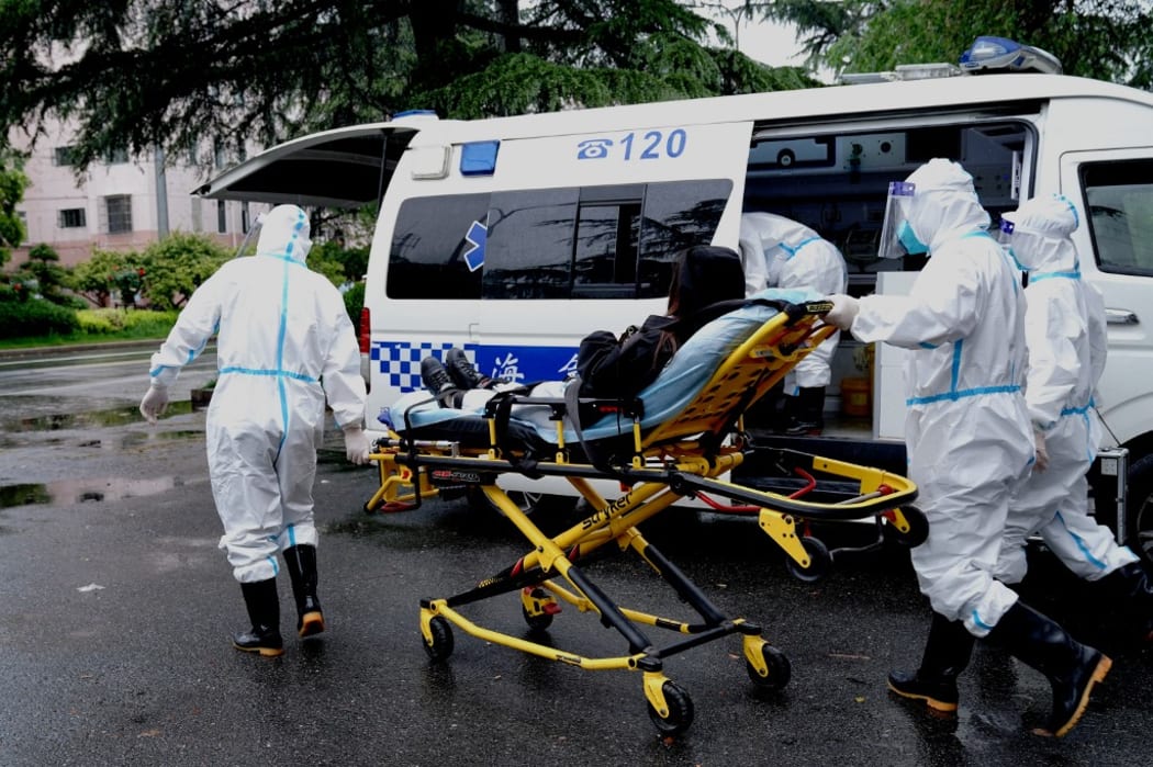 Medical workers of the medical emergency center of Minhang District of Shanghai transfer a patient onto an ambulance in Shanghai, east China, April 23, 2022.