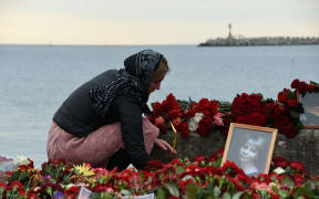 A woman lights a candle next to flowers and a portrait of one of the victims, famous Russian charity activist and founder of the Voters' League Elizaveta Glinka or Dr Liza, at a makeshift memorial at the embankment on the shore of the Black Sea in Sochi.