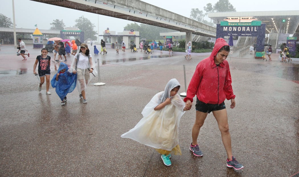 People leave Disney's Magic Kingdom theme park, in heavy rain, after it closed in Orlando, Florida