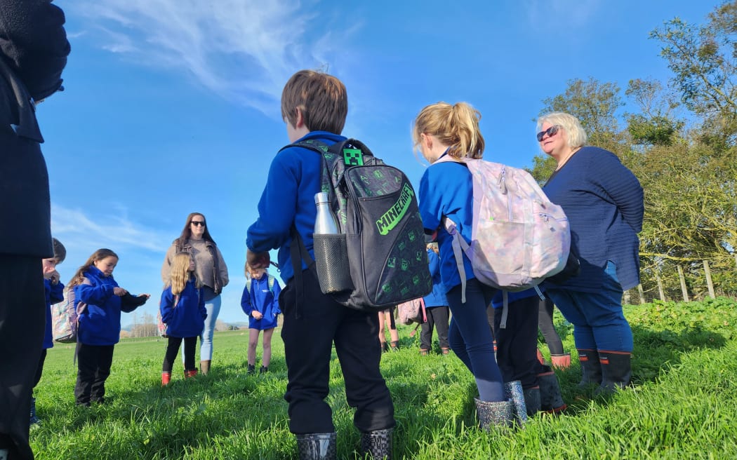 The children gather for karakia with teacher Lara Hooper in the paddock