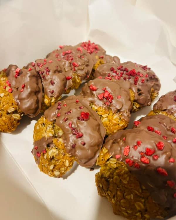 A stack of large cookies half coated in chocolate.
