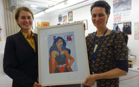 Catherine Bisley, left, and Ariana Tikao, right, both curators at the Turnbull Library, holding a piece of art by Robyn Kahukiwa.