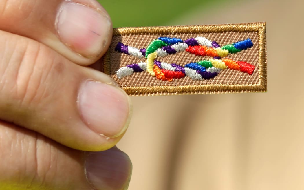 A member of Scouts for Equality holds an unofficial knot patch incorportating the colors of the rainbow, a symbol for gay rights.