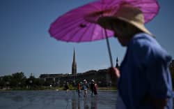 Visitors walk across the Mirroir d’Eau reflecting pool to cool down in Bordeaux, southwestern France on June 23, 2026, as France experiences a heatwave. (Photo by Christophe ARCHAMBAULT / AFP)