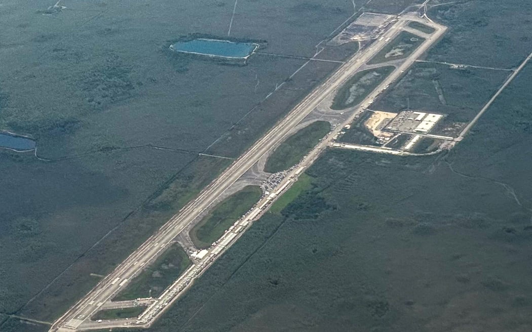An aerial view of a migrant detention center, dubbed "Alligator Alcatraz," is seen located at the site of the Dade-Collier Training and Transition Airport in Ochopee, Florida on July 7, 2025. The $450 million camp has been built on a disused airfield deep in the Florida Everglades and is surrounded by swamps that are home to creatures including alligators and poisonous snakes. The steaming hot, mosquito-infested site is a symbol of the Republican administration's determination to look tough as it pursues its policy of mass deportations of undocumented migrants. (Photo by CHANDAN KHANNA / AFP)