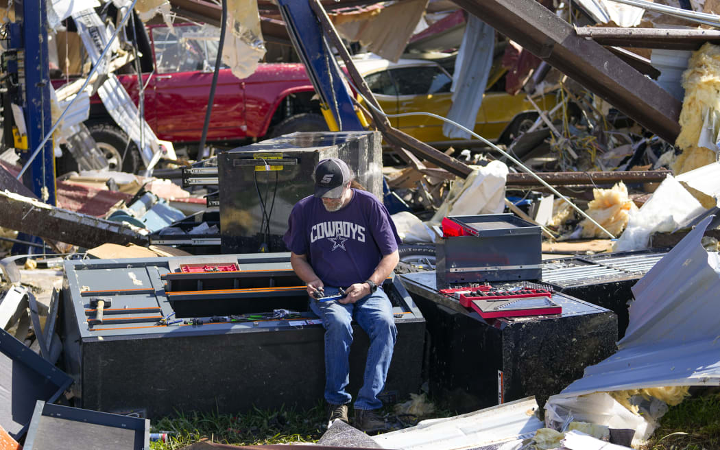 An employee of a body shop collects tools from near damage the morning after a tornado rolled through, Sunday, 26 May, 2024, in Valley View, Texas.