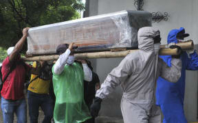 Relatives of a person who died from Covid-19 carry the wrapped coffin inside a cemetery in Ecuador yesterday.