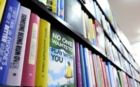 A series of books on a shelf, one title in focus "No one wants to play with you".