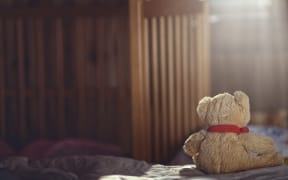 Teddy bear in an empty child's room.