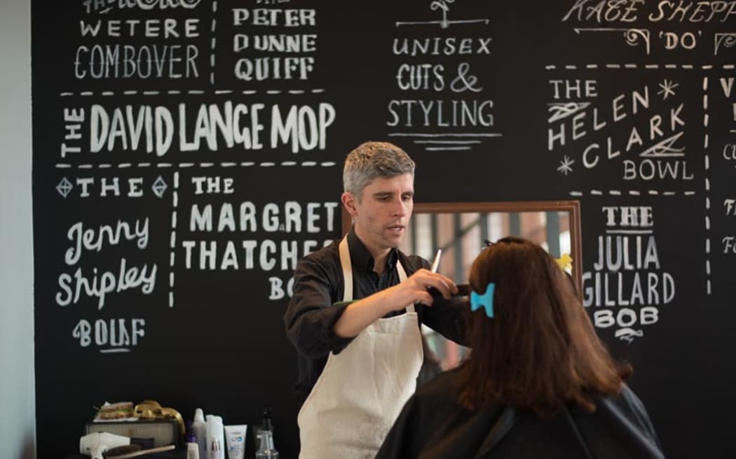 Jason Muir cutting hair in his performance hair salon Political Cutz.