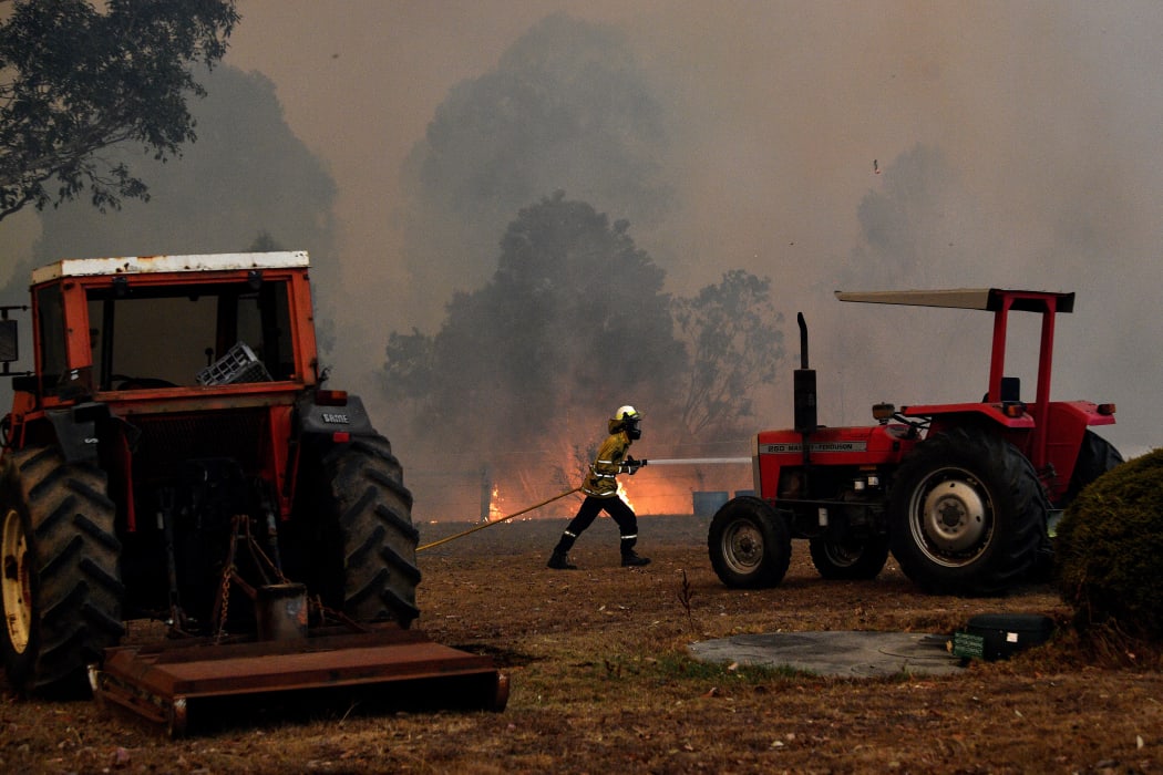 A firefighter trying to stop a fire reaching a house near the NSW town of Nowra, on December 31, 2019.