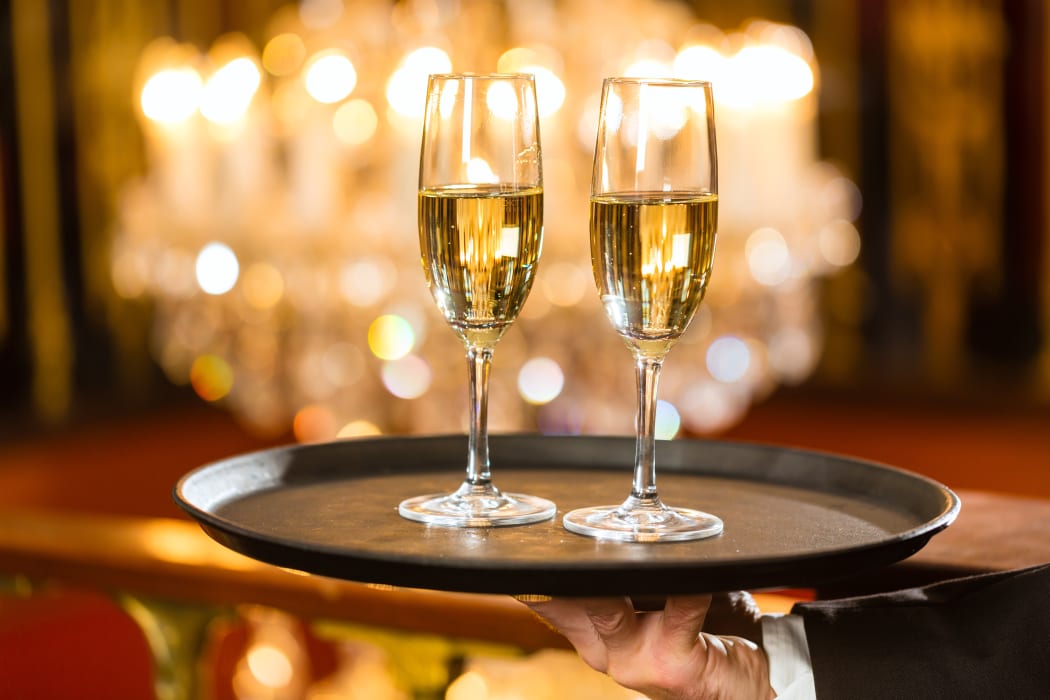 A waiter holds two glasses of champagne, at a gala dinner (file).