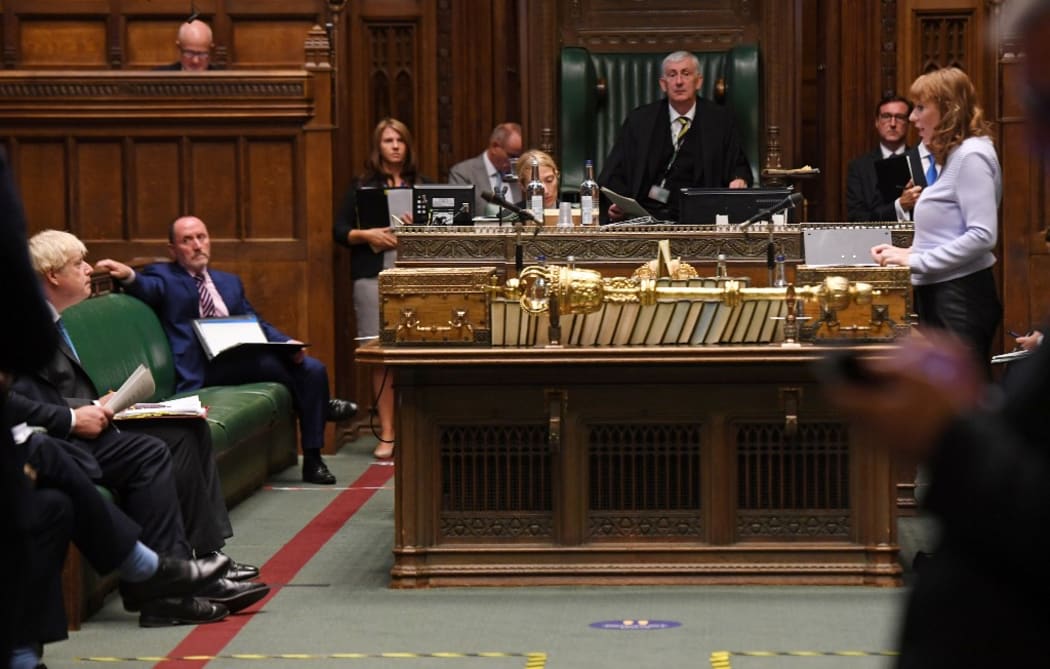A handout photograph released by the UK Parliament shows Britain's Prime Minister Boris Johnson (L) listening as Britain's main opposition Labour Party deputy leader Angela Rayner speaks during Prime Minister's Questions (PMQs).