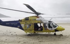 A rescue helicopter is seen on the central Queensland coast, where its crew rescued a man in his 70s who swam nine hours through the night after falling from his catamaran in rough conditions.